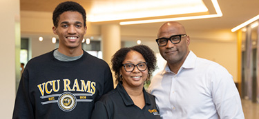 A family of son, mother and father stand together in VCU apparel