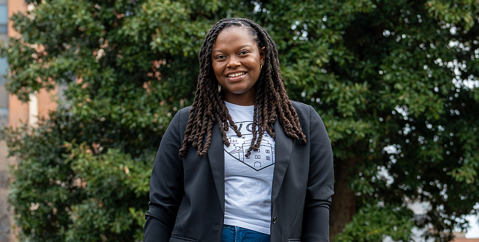 A student wearing a VCU shirt stands in front of trees